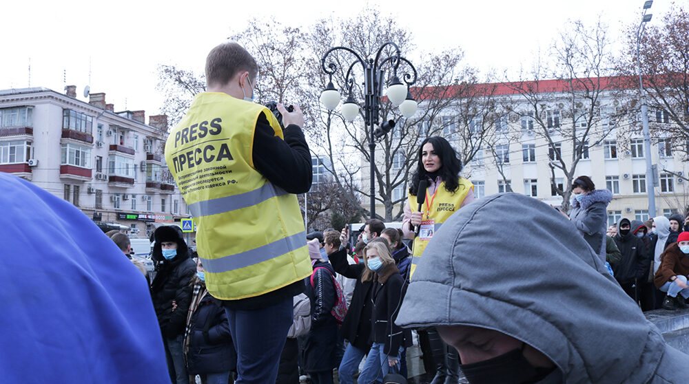 Reporter och fotograf intervjuar demonstranter i Ryssland.