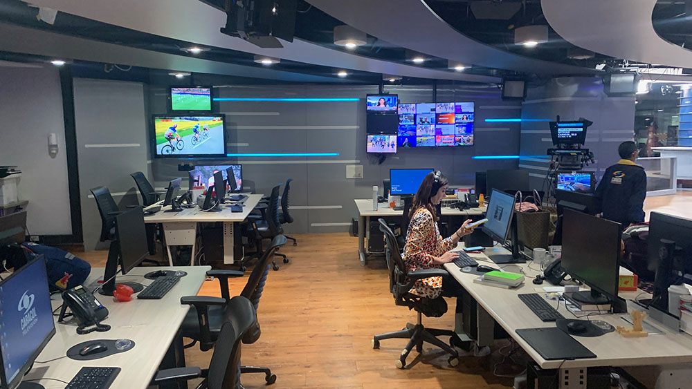 En tv-station i colombia, skärmaroch en reporter vid ett skrivbord